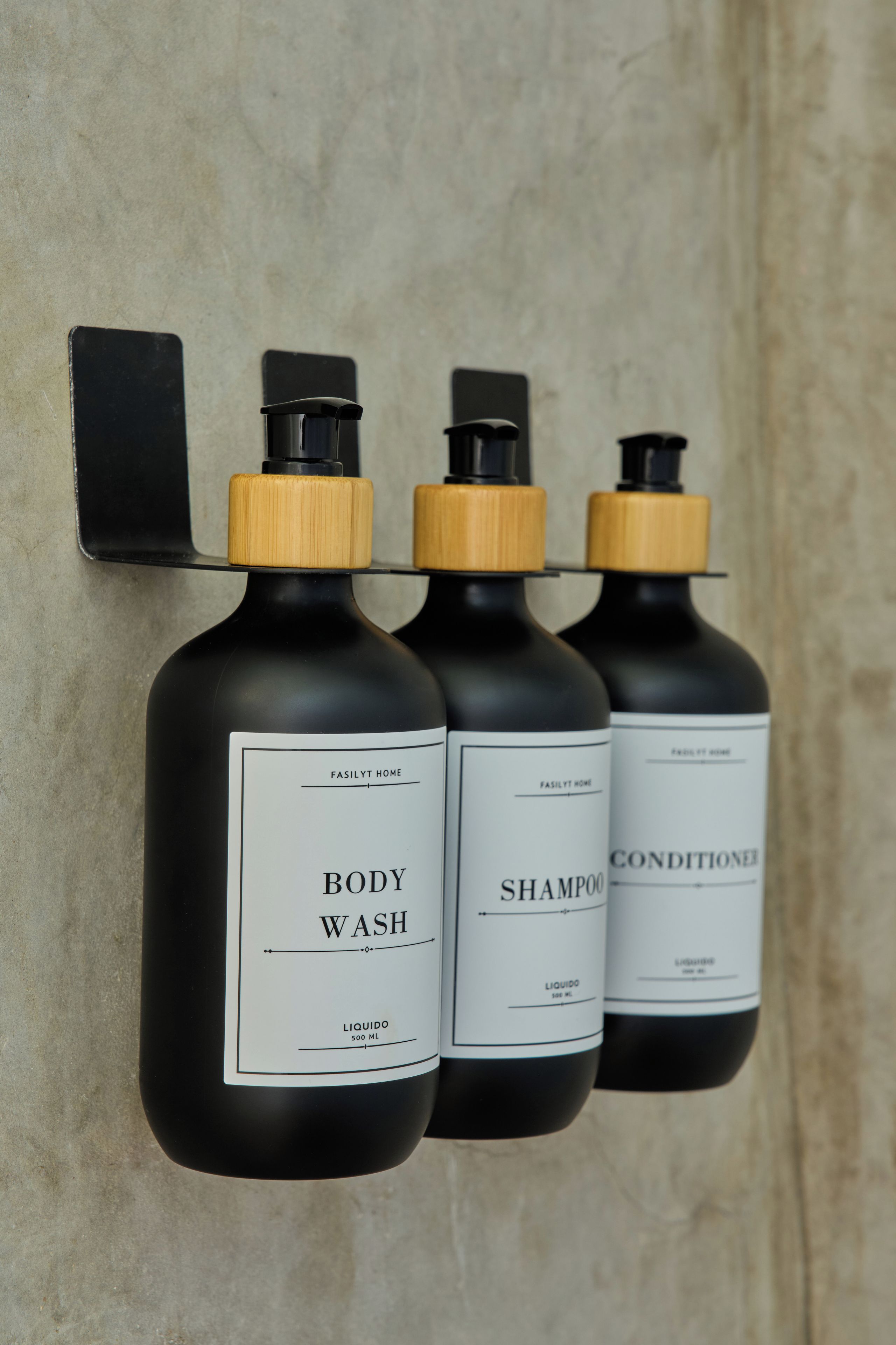 Three bottles of liquid on a wall-mounted holder.