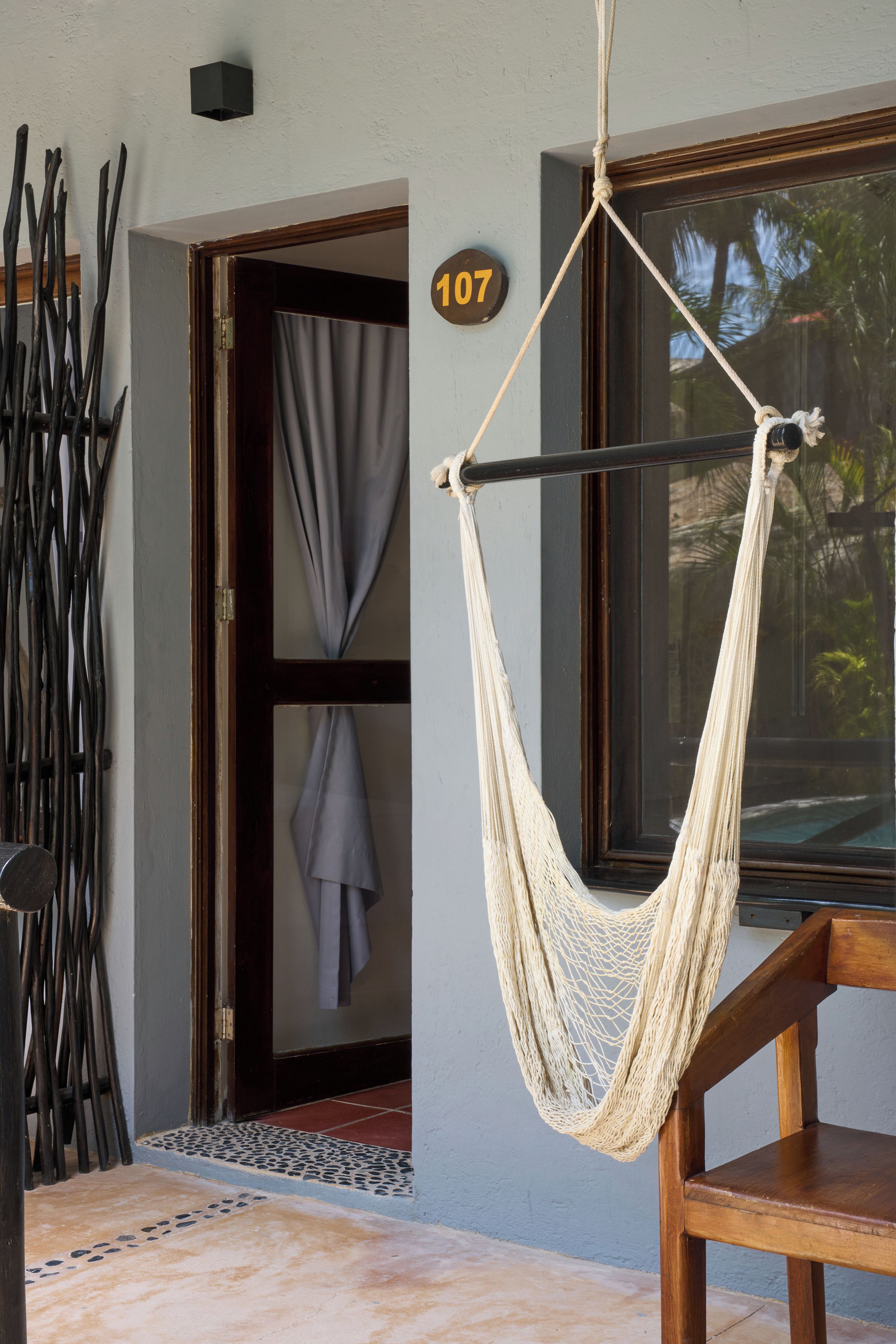 A hammock hanging by a window, a door with a curtain, and a number '107' on the wall.
