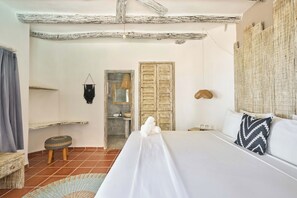 A bedroom with a bed, a wooden door, a small stool, and a wall-mounted shelf. - Holbox Dream Beach Front Hotel  (Isla Holbox)