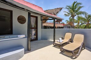 A balcony with two lounge chairs, a small pool, and a thatched-roof structure in the background. - Holbox Dream Beach Front Hotel  (Isla Holbox)