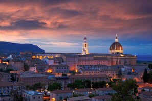 A historic building complex with a prominent dome and bell tower, surrounded by residential buildings. - San Francesco Hotel (Loreto)