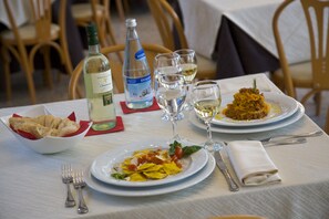 A dining table with plates of food, glasses, and cutlery.