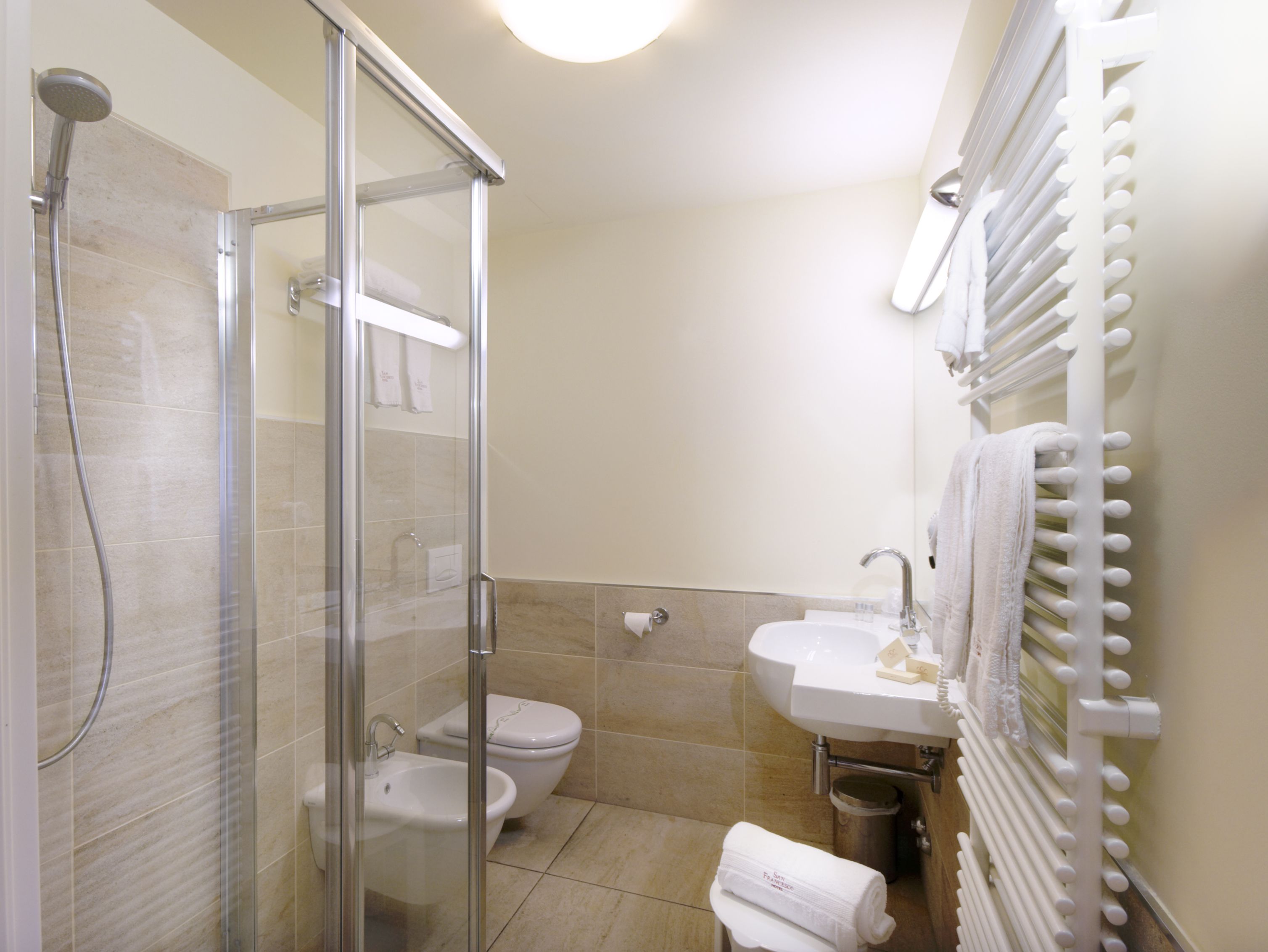 A bathroom with a glass-enclosed shower, a toilet, a sink, and a towel rack.