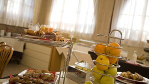A buffet table with various food items including fruits, pastries, and a fruit display. - San Francesco Hotel (Loreto)