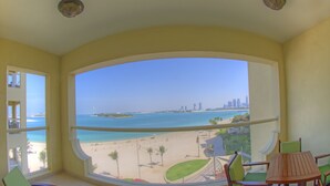 A balcony with a view of a beach and a city skyline.