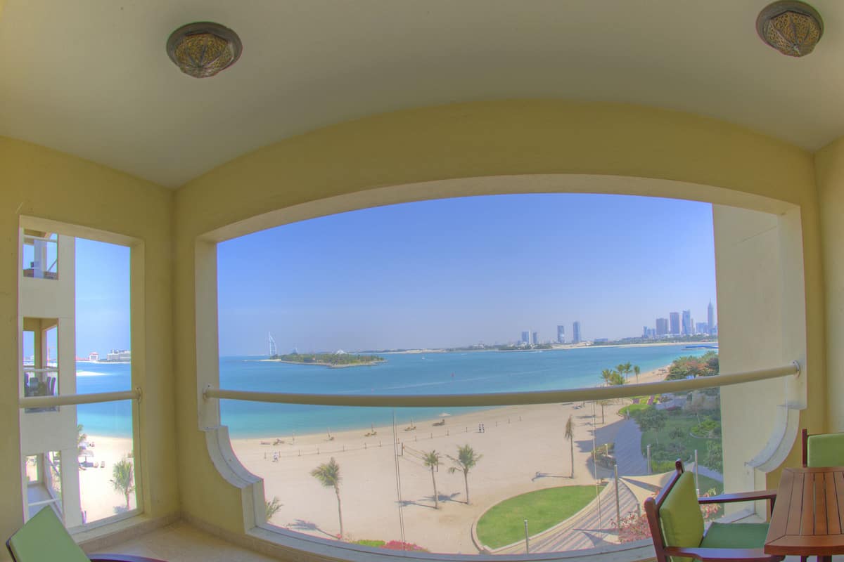 A balcony with a view of a beach and a city skyline.