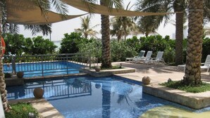 A pool area with lounge chairs and palm trees.