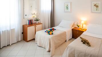 Two beds with matching headboards, a bedside table, and a small cabinet create a comfortable space.
