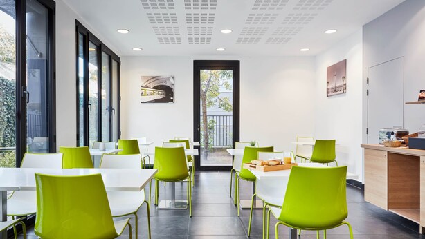 A modern dining area with green chairs and white tables, large windows, and a view of the outdoors. - Aparthotel Adagio Access Paris Bastille (Paris)