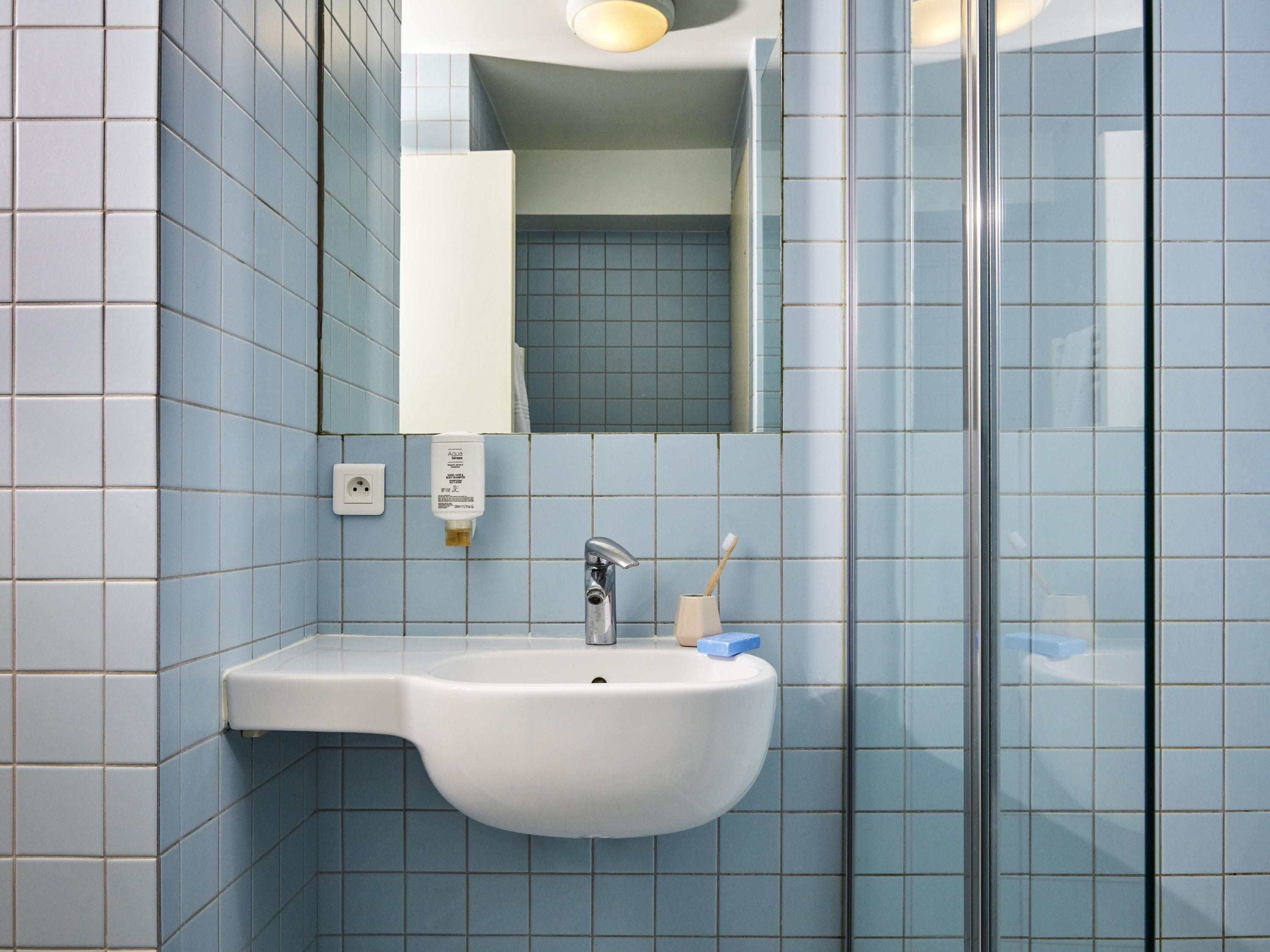 A bathroom with a white sink, a mirror, and a glass shower enclosure.