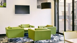 A modern hotel lobby with green seating, a flat-screen TV, and artwork on the walls. - Aparthotel Adagio Access Paris Bastille (Paris)