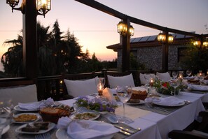 An outdoor dining area with tables set for a meal, featuring candles and a view of the sunset. - Mandarin & Mango Boutique Hotel (Fethiye)