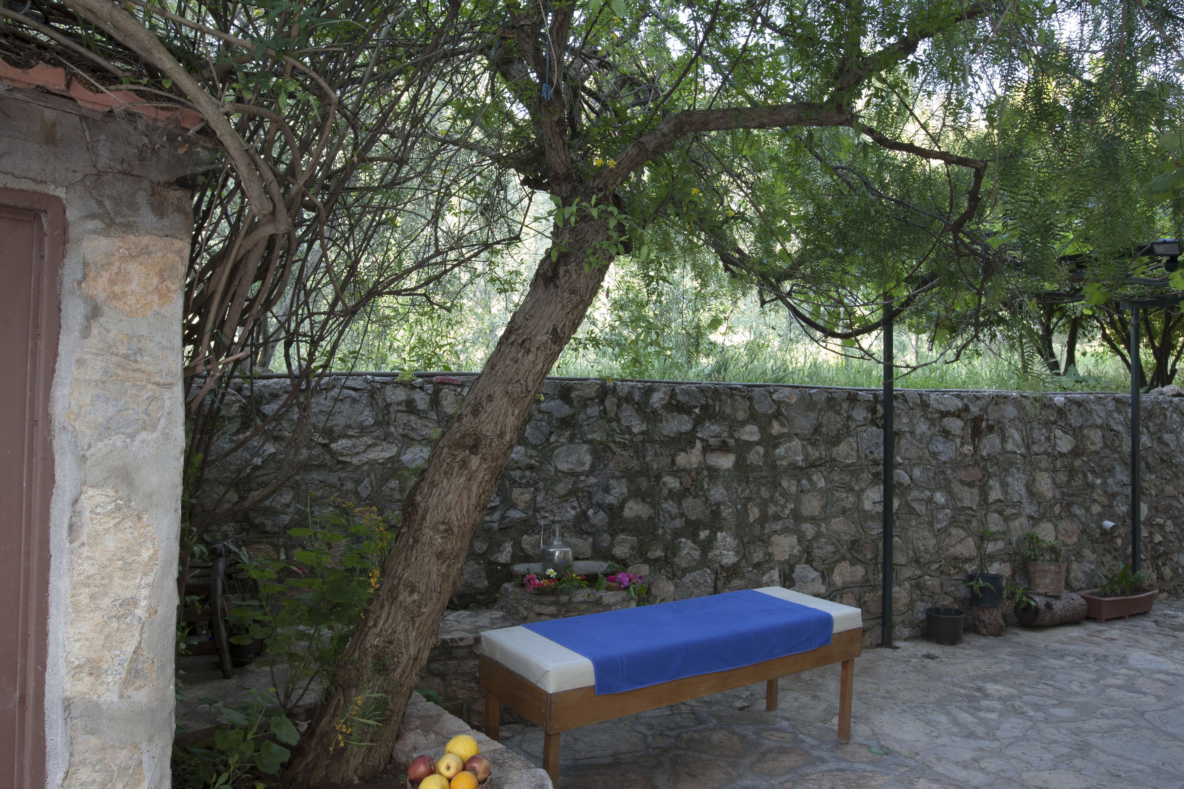 A stone wall, a wooden bench with a blue cover, and potted plants.