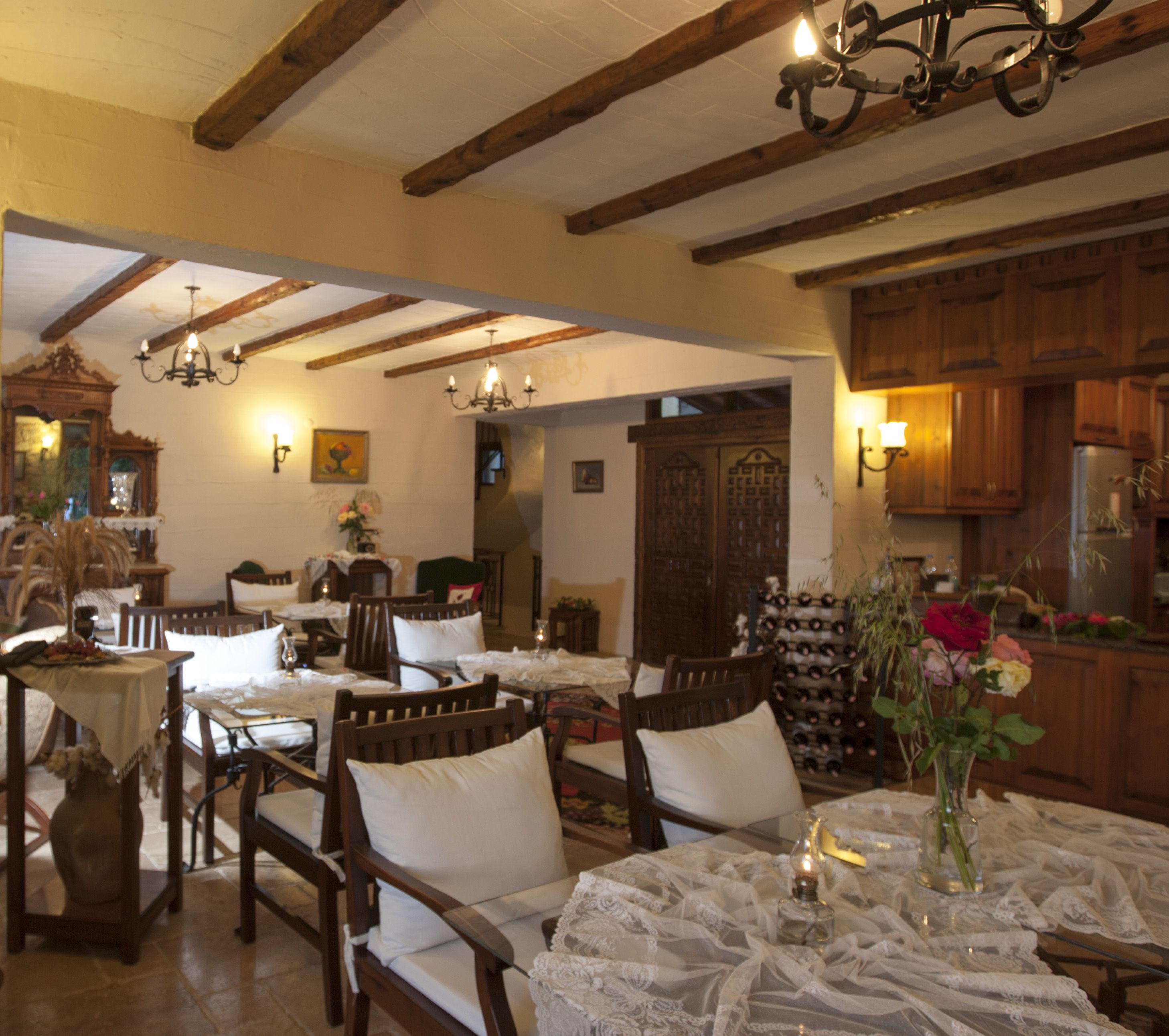 Un comedor con mobiliario de madera y una araña. Se observa una estantería para vinos al fondo.