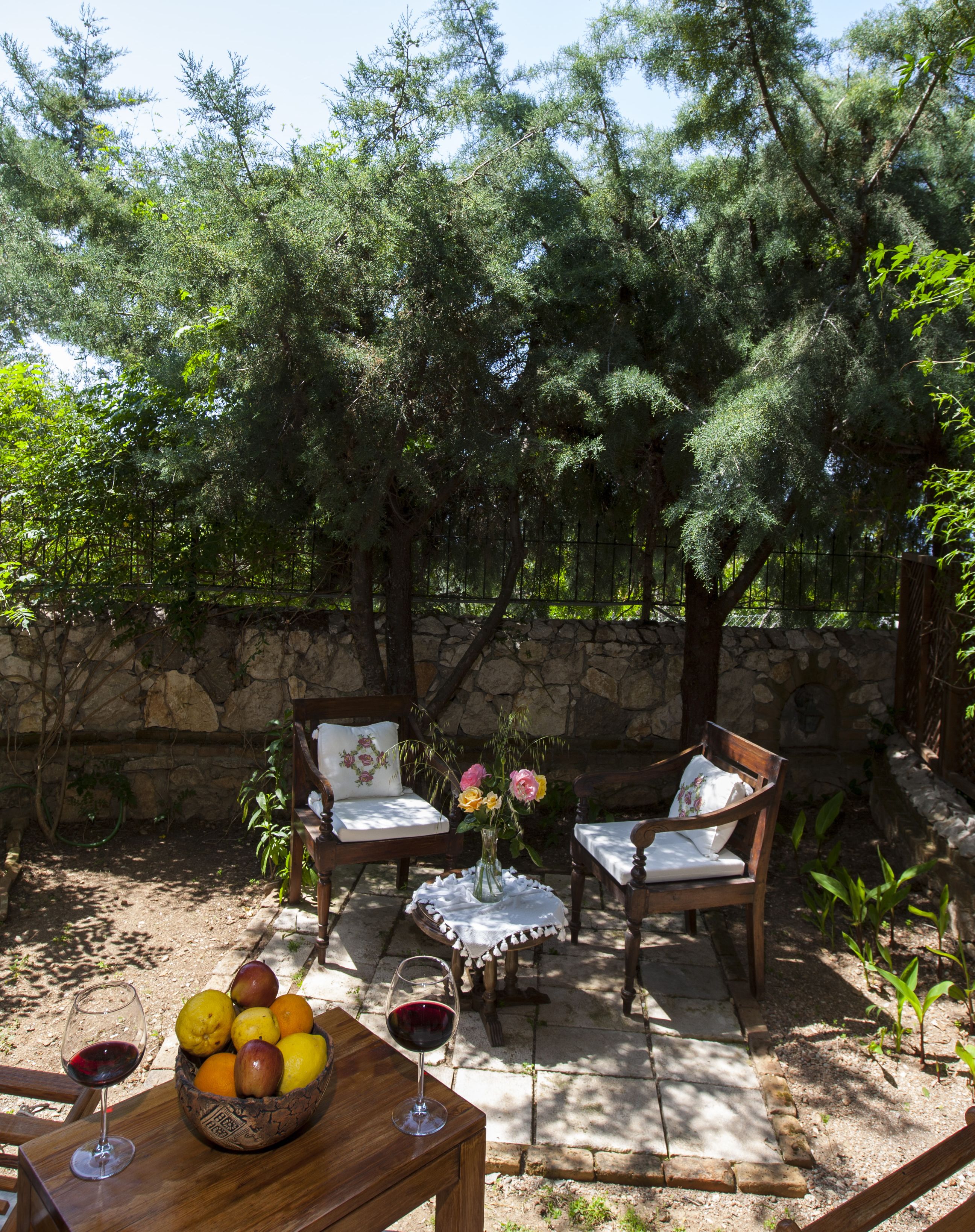 Un espace extérieur aménagé avec des murs en pierre, du mobilier en bois et une table sur laquelle sont disposés des fruits et des verres à vin.