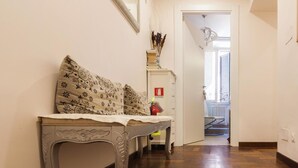 A hallway with a wooden floor, a bench with patterned cushions, and a door leading to a balcony. - La Piccola Maison (Rome)