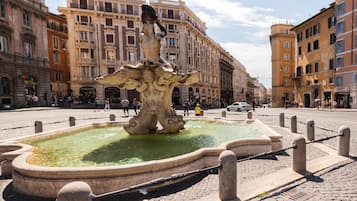A historic fountain with intricate carvings in a public square, surrounded by classic European architecture.