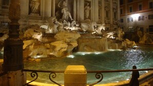 A nighttime view of the Trevi Fountain with its sculptures and water features. - La Piccola Maison (Rome)