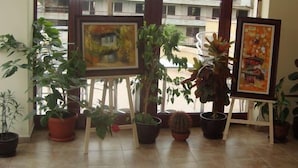 Una habitación con macetas y cuadros sobre caballetes.