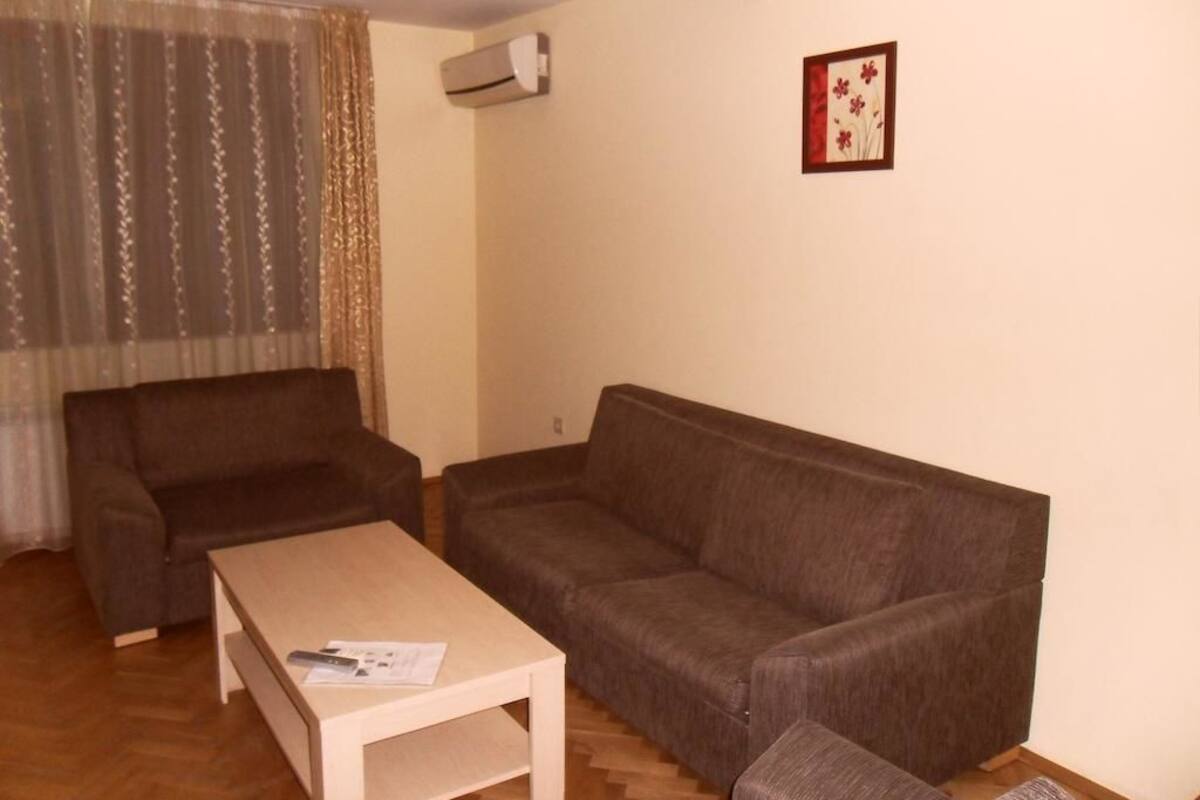 A living room with a sofa, a coffee table, and a small table with a remote control.