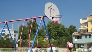 Un patio de recreo con un aro de baloncesto y columpios.