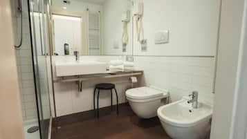 Un bagno moderno con box doccia in vetro, lavandino bianco, bidet e specchio.