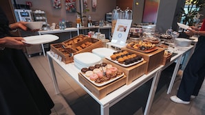 A buffet table with various food items and a digital menu board.
