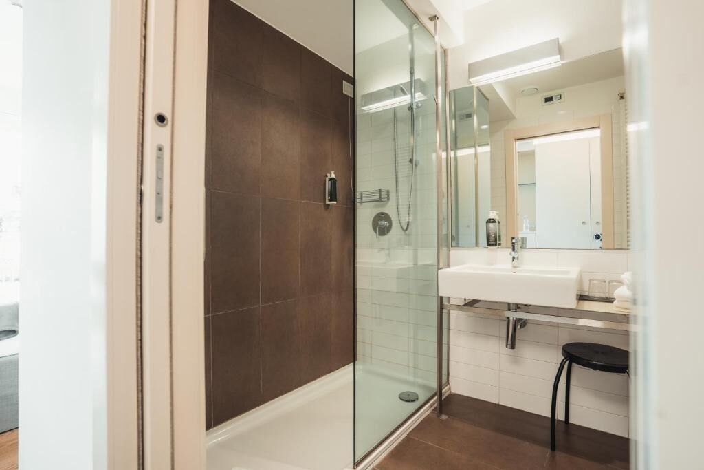 Ein modernes Badezimmer mit einer Duschkabine aus Glas, einem weißen Waschbecken und einem Spiegel darüber.
