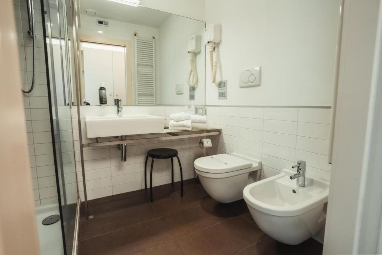 Un baño moderno con cabina de ducha de vidrio, lavamanos blanco, bidé y espejo.