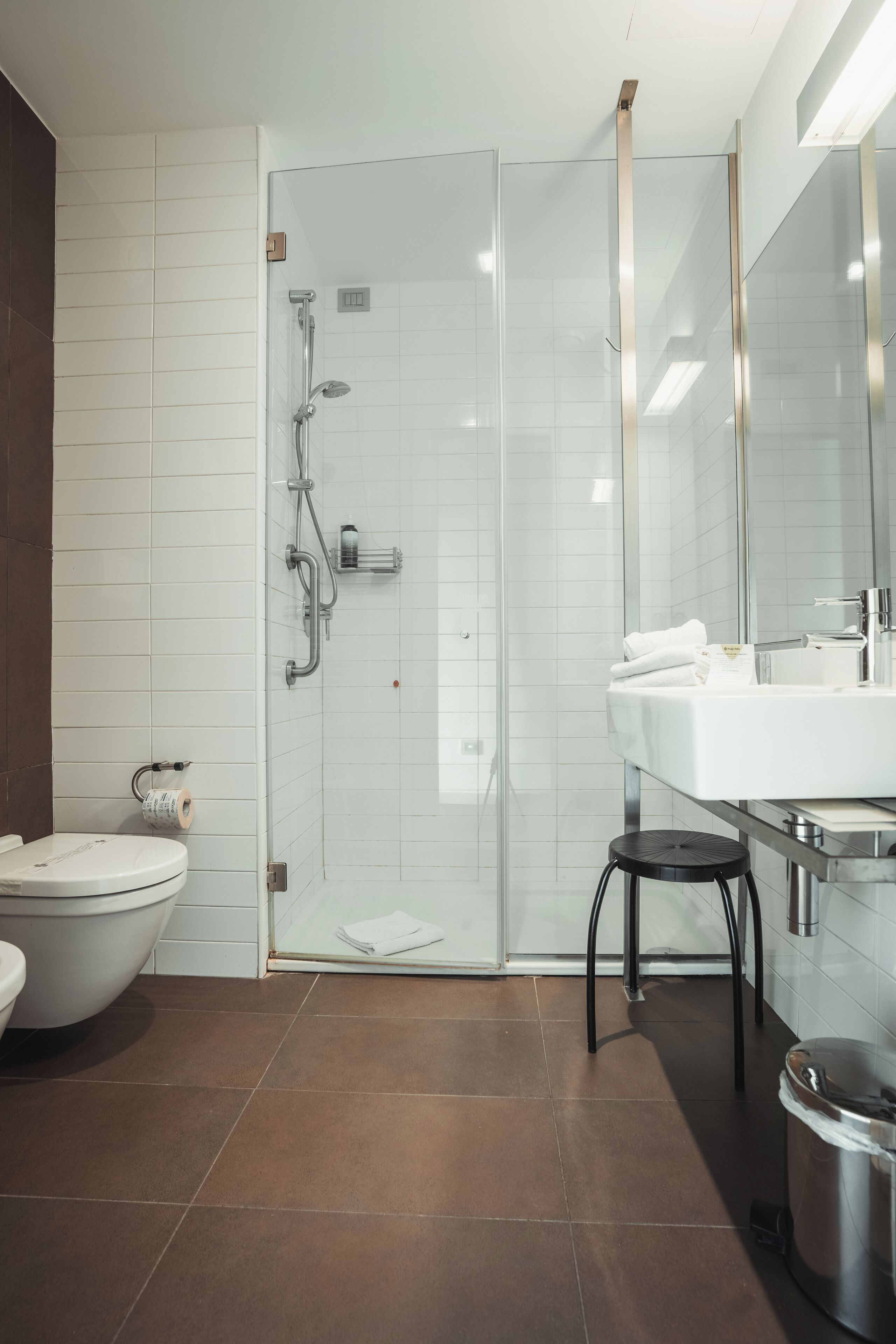 A modern bathroom with a glass-enclosed shower, a white sink, and a toilet.