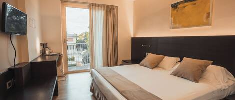 Una habitación de hotel moderna con una cama grande, televisión de pantalla plana, escritorio y balcón con cortinas.