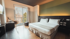 A modern hotel room with a large bed, a desk, and a chair.