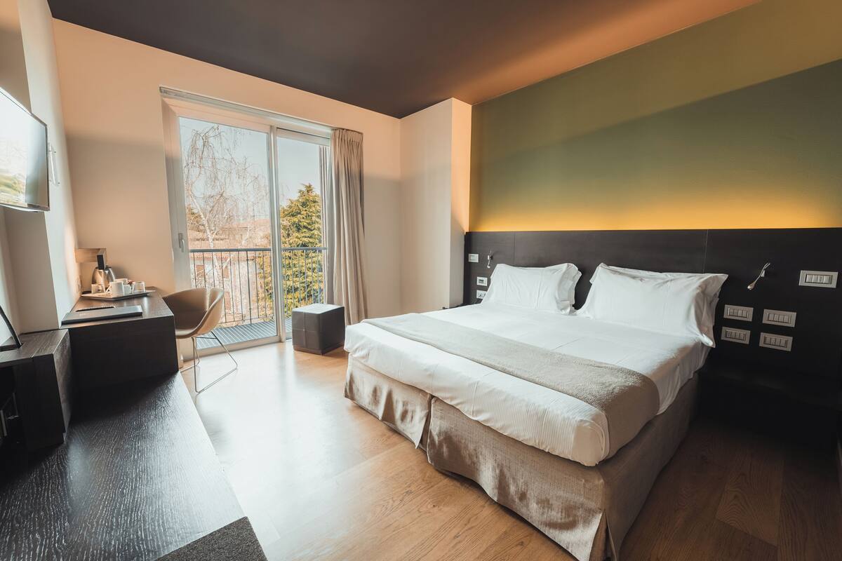 A modern hotel room with a large bed, a desk, and a chair.