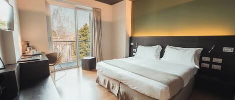 A modern hotel room with a large bed, a desk, and a chair.