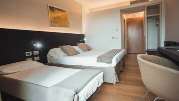 Ein Hotelzimmer mit zwei Einzelbetten, einem Schreibtisch und einem Stuhl.