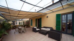 A covered patio area with outdoor furniture, including a sofa and chairs, and a dining table. - Hotel Globo Suite (Sanremo)