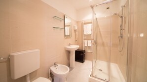 A modern bathroom with a toilet, bidet, sink, and glass-enclosed shower. - Hotel Globo Suite (Sanremo)