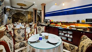 Ein Restaurant mit verzierten Stühlen, einem Buffet mit verschiedenen Speisen und einer dekorativen Decke.
