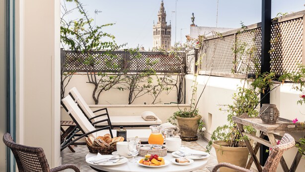 A round table with breakfast items, wicker chairs, and a view of a historic tower.