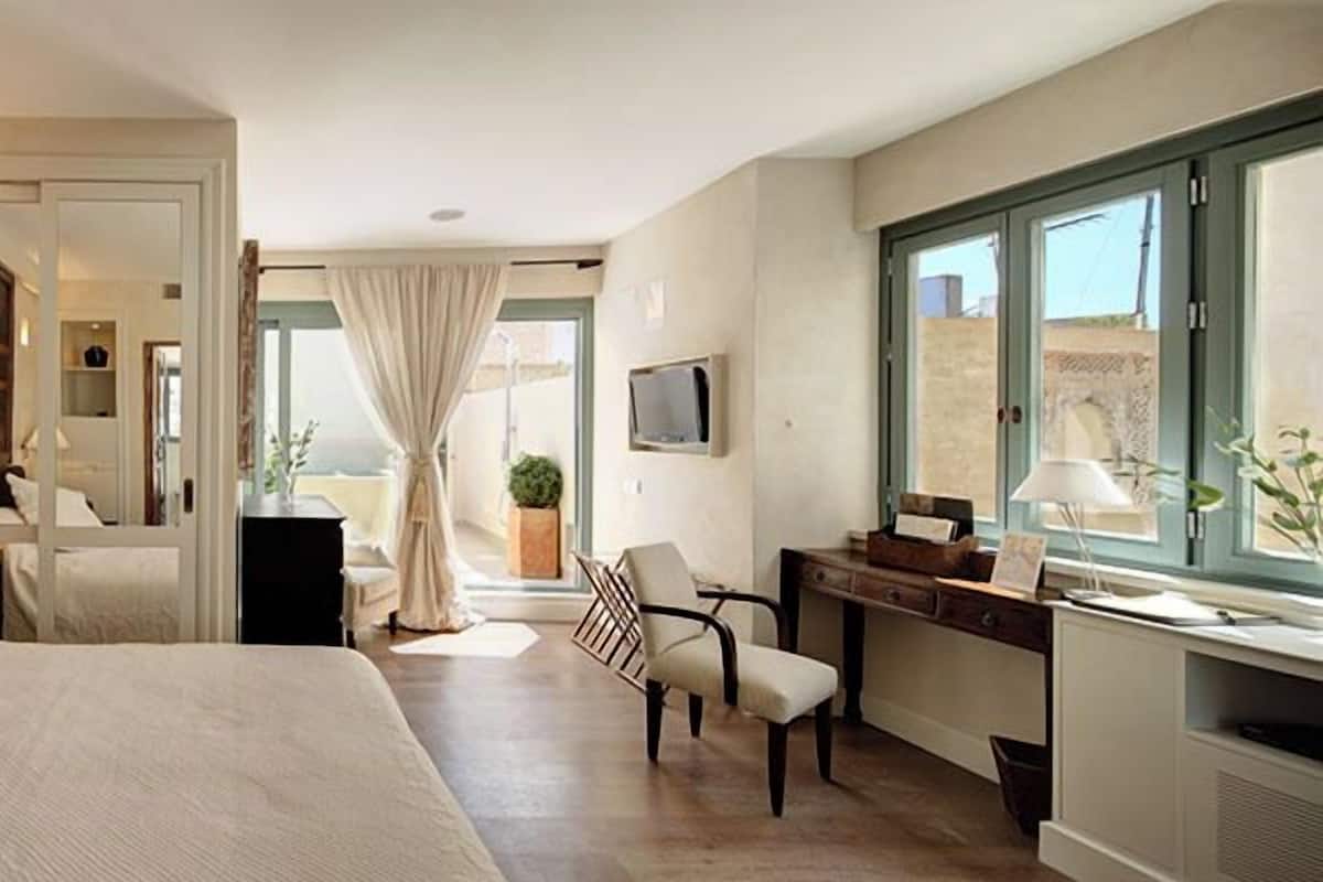 A hotel room with a bed, a desk, a chair, and a large window.