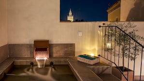 A spa area with a hot tub, a small wooden bench, and a staircase with a railing.