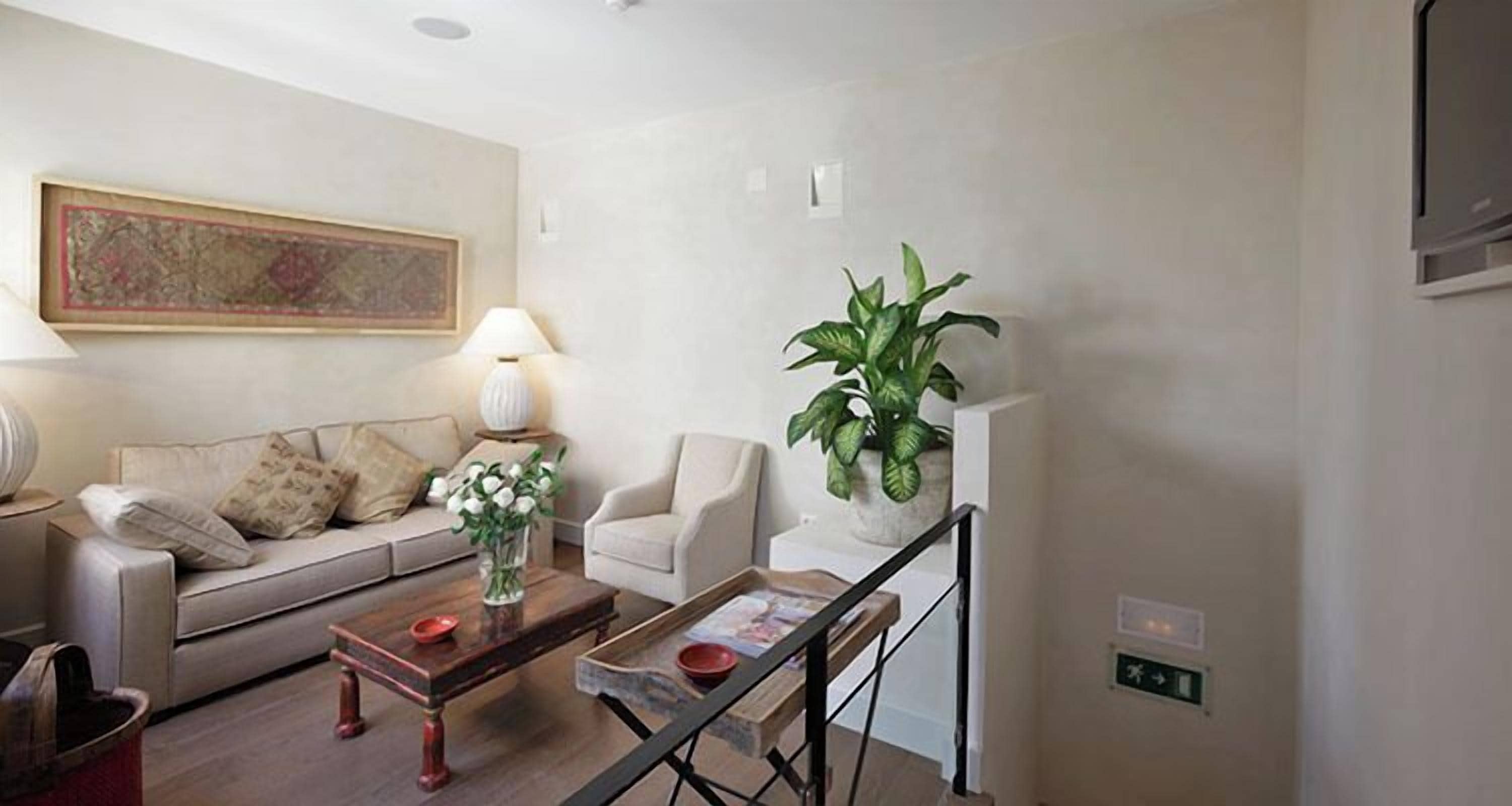 Una sala de estar con sofá, sillones, una mesita de centro, una lámpara y una planta en maceta.