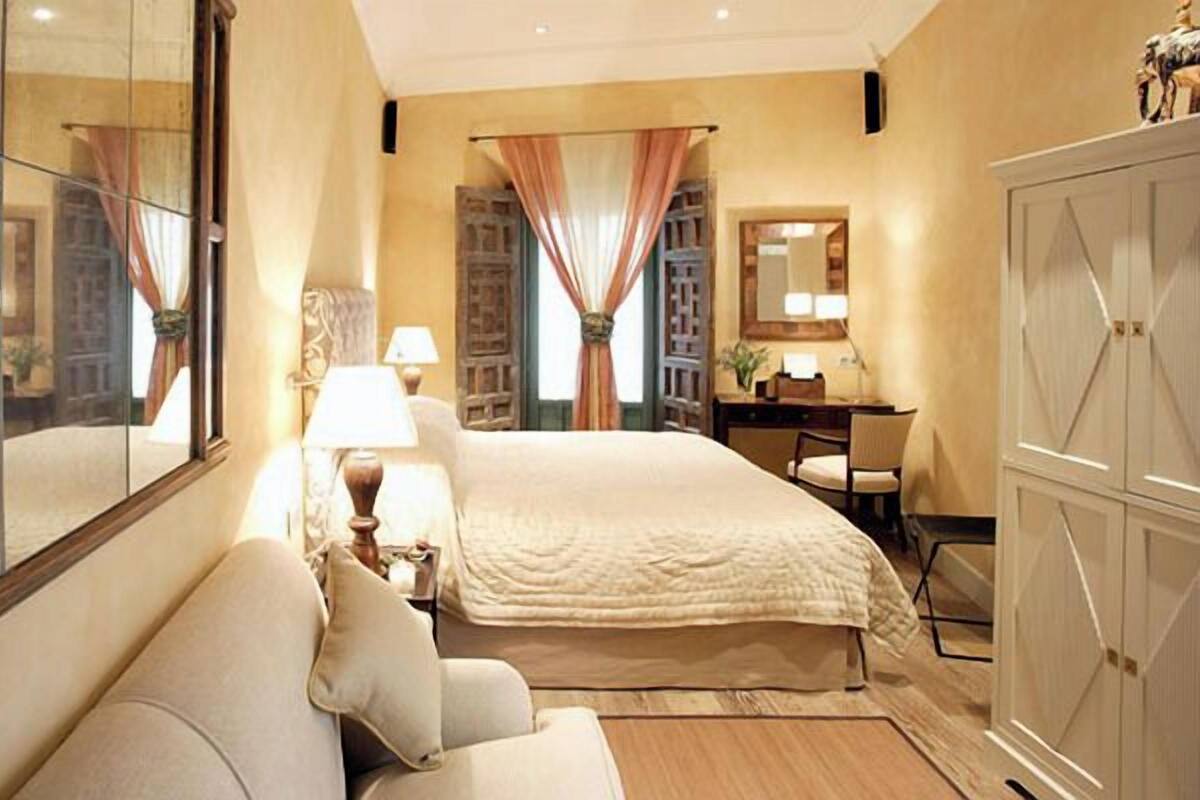 A hotel room with a large bed, a sofa, a desk, and a wardrobe.