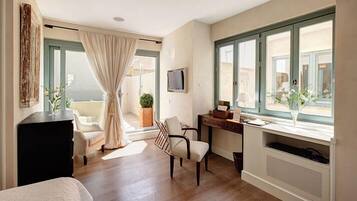 A hotel room with a bed, a desk, a chair, a TV, and a window with a view of the outside.