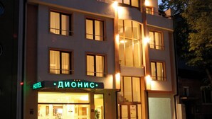 Un hôtel doté d’une façade moderne, de nombreuses fenêtres et d’une enseigne lumineuse indiquant qu’il s’agit de l’hôtel « Dionis ».