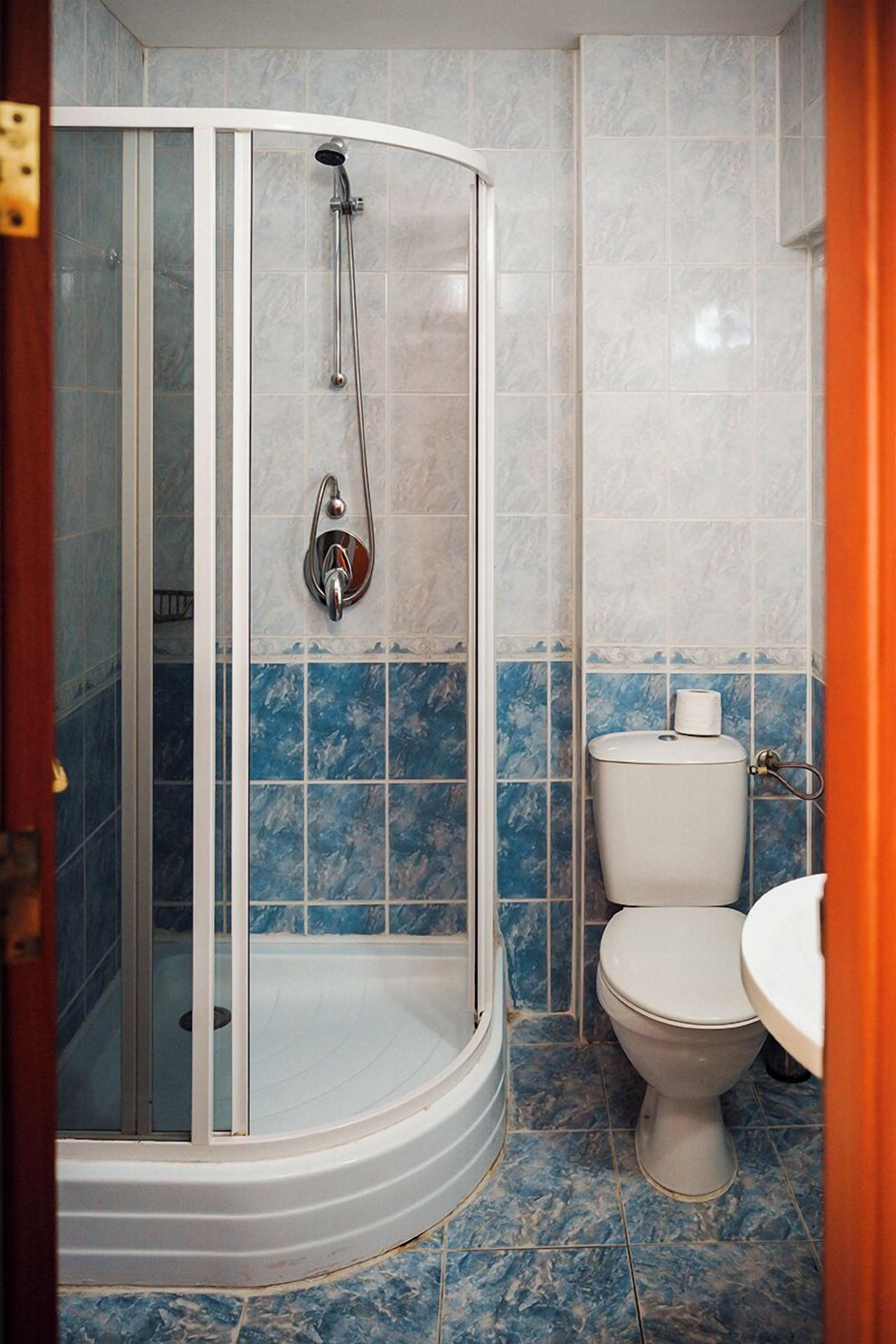 Et badeværelse med en brusekabine i glas, toilet og håndvask.