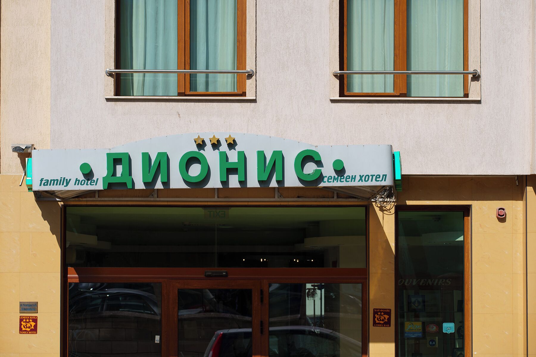 A hotel entrance with a sign reading "DIONIC family hotel" and a visible entrance door.