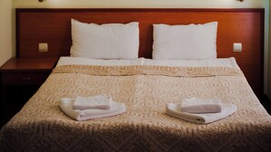 Un lit bien fait, avec une couvre-lit à motifs et deux serviettes pliées posées au pied du lit.
