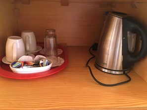 A compact kitchenette with a stainless steel kettle, a coffee maker, and a tray with cups and a thermos. - Kiniras Traditional House (Paphos)