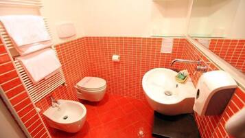 Ein Badezimmer mit roten Fliesen, einem weißen Waschbecken, einem Bidet und einer Toilette.